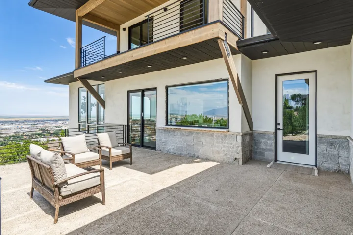 Expansive concrete patio area with a stone base, large windows, and a glass-paneled exterior door