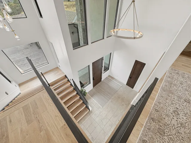 Grand entryway featuring a two-story ceiling, light wood-finish flooring, and a contemporary chandelier