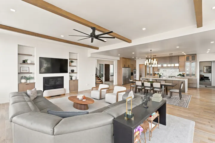 Open-concept living space featuring wood-finish flooring, exposed ceiling beams, and recessed lighting