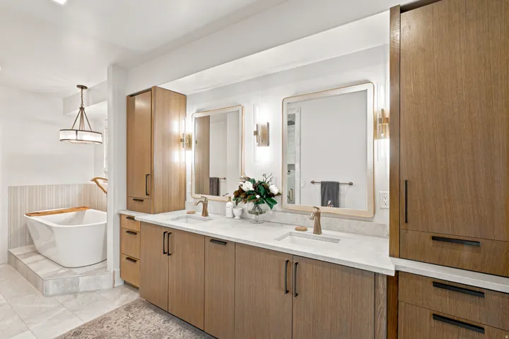 Dual vanity featuring wood-finish cabinetry, white stone countertops, and integrated rectangular sinks