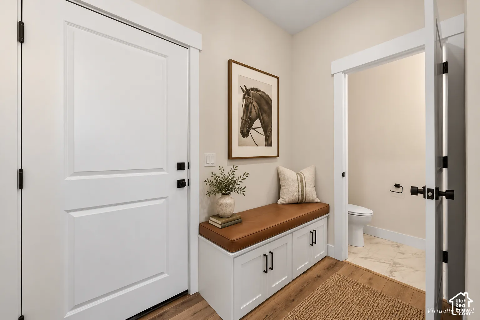 Entryway featuring white shaker-style built-in cabinetry, wood-finish flooring, and matte black door hardware