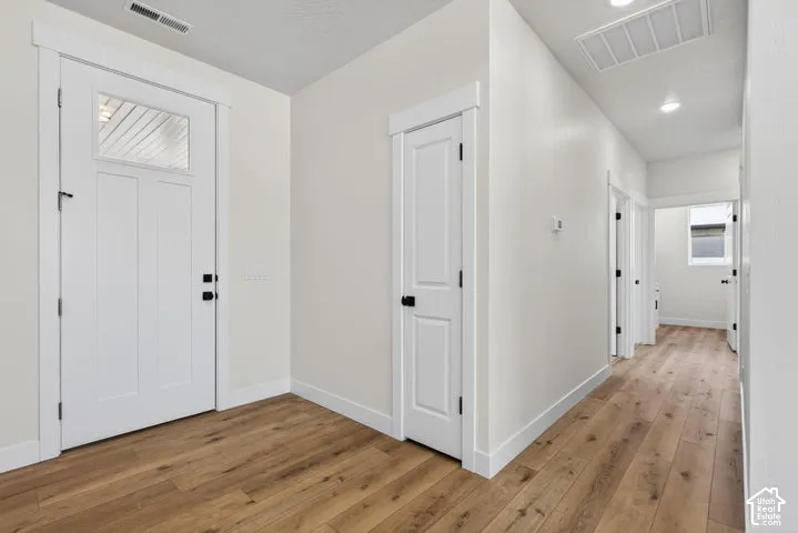Entryway featuring wood-finish flooring, a white paneled front door with a glass inlay, recessed ceiling lighting, and matte black hardware