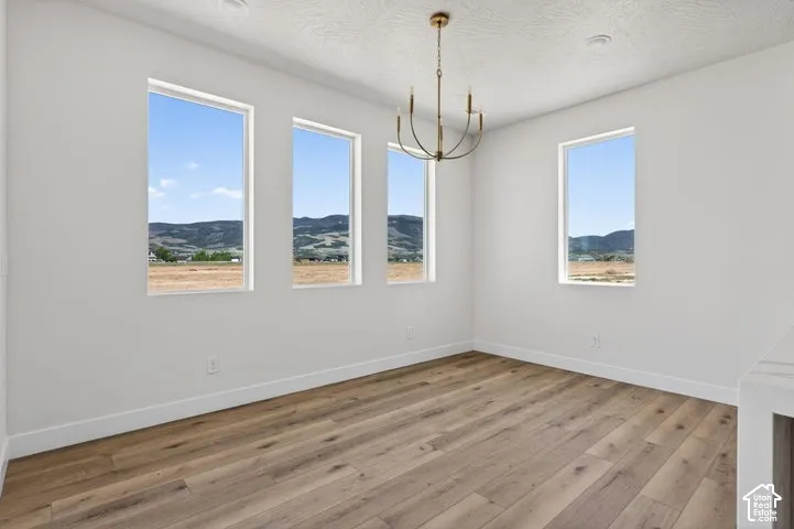 Room featuring wood-finish flooring, four vertical windows with mountain backdrops, and a brass-tone chandelier