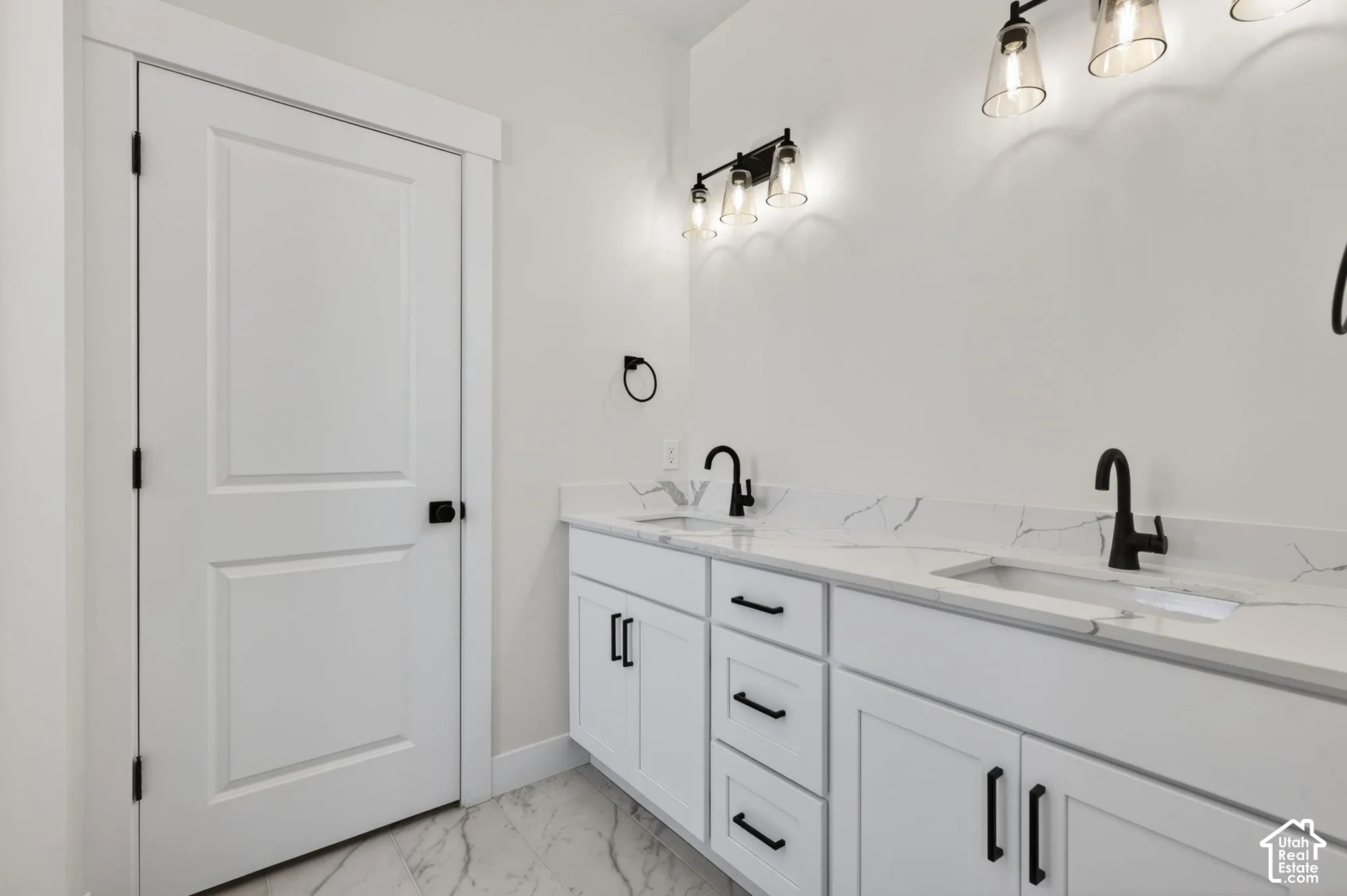 Dual vanity with bright white cabinetry, integrated sinks, white countertops with subtle veining, and matte black hardware