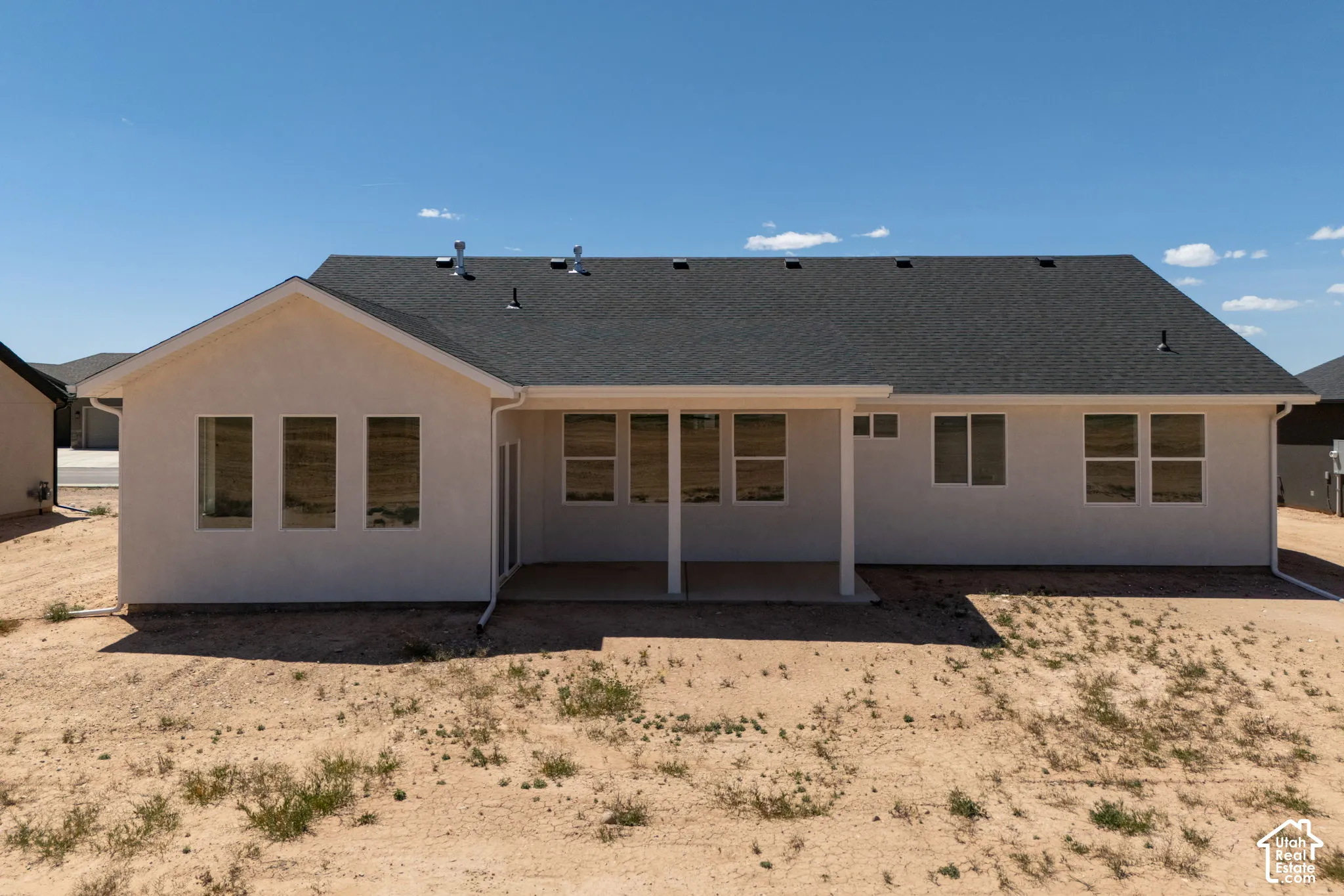Rear exterior featuring a covered patio, multiple windows, and a dark shingle roof