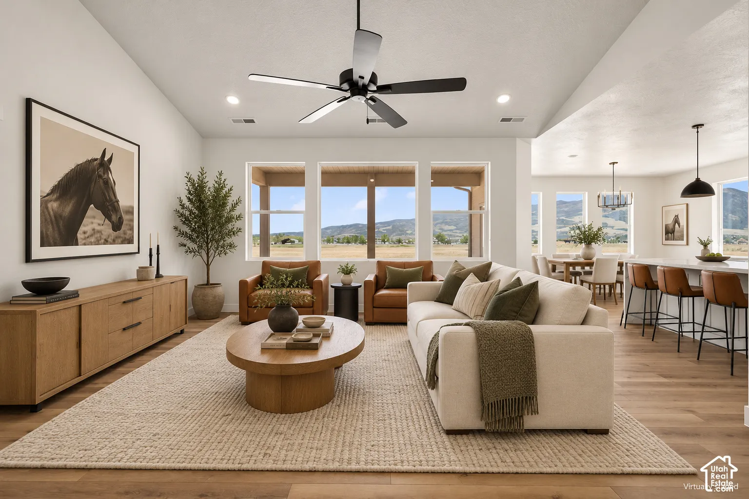Vaulted ceiling featuring a central black matte ceiling fan, expansive triple-pane window arrangement, and wood-finish flooring throughout