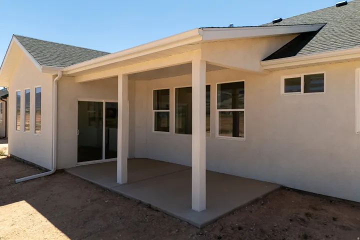 Covered concrete patio extending from the stucco exterior