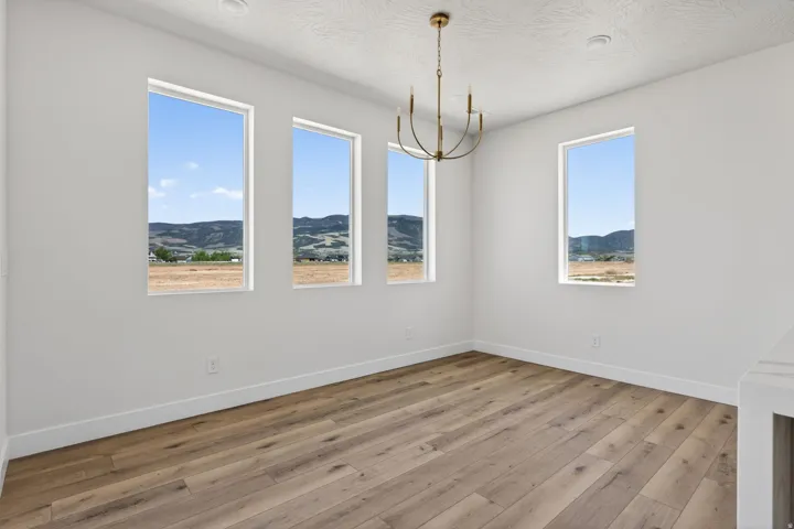 Spacious room featuring four tall windows, wood-finish flooring, and a contemporary brass chandelier