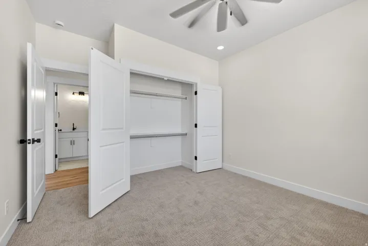 Carpeted room featuring a ceiling fan, recessed lighting, and a built-in closet with shelving and hanging rods