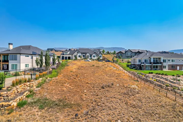 Expansive vacant land with fenced perimeter and gated entry, situated in an established residential community