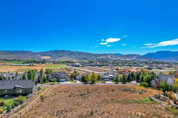 Expansive undeveloped parcel with a partial wood fence, surrounded by residential properties, and featuring distant mountain scenery