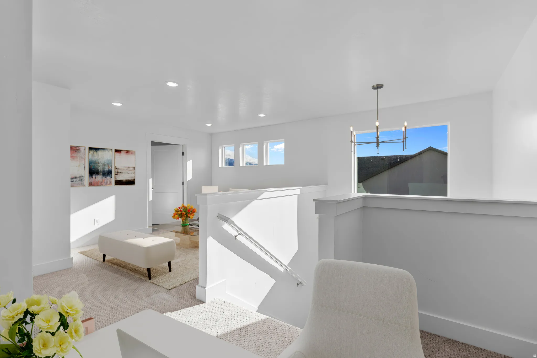 Modern open-concept living space featuring clean white walls, recessed ceiling lighting, and abundant natural light from multiple windows