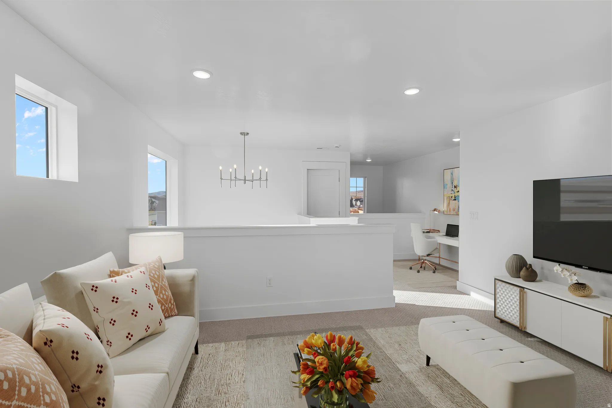 Open-concept living area featuring a modern kitchen with a white waterfall-edge island, stainless steel appliances, and pendant lighting