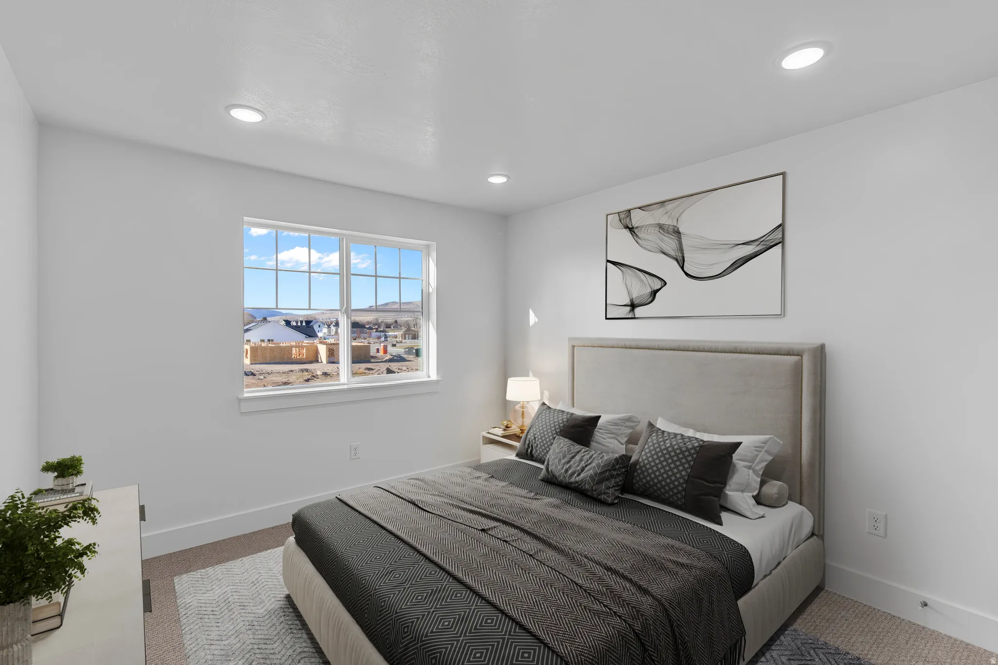 Bright bedroom with expansive multi-pane window framing panoramic city vistas, neutral upholstered headboard with wood-frame detailing, recessed ceiling lighting, wood-finish flooring, area rug, and contemporary abstract wall art
