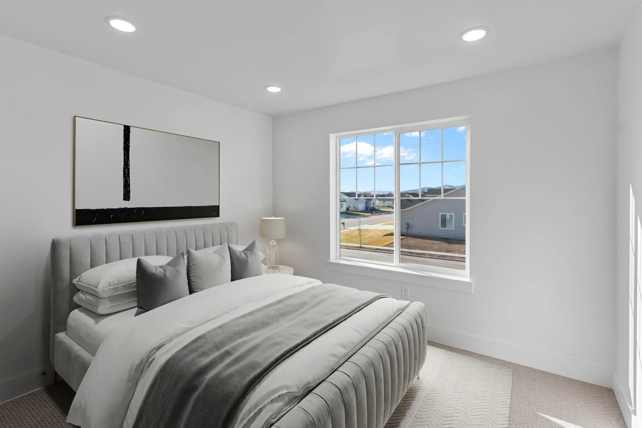 Bright bedroom featuring a large multi-pane window, recessed lighting, and light-toned carpeting