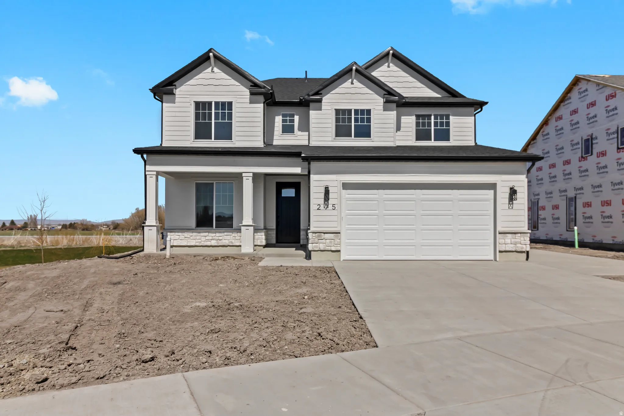 Striking two-story colonial with crisp cream and charcoal exterior featuring dual peaked rooflines, multiple gabled sections, and architectural detail