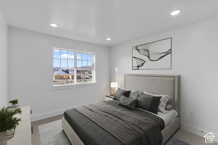 Bright bedroom with expansive multi-pane window framing panoramic city vistas, neutral upholstered headboard with wood-frame detailing, recessed ceiling lighting, wood-finish flooring, area rug, and contemporary abstract wall art