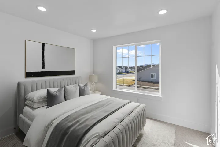 Bright bedroom featuring a large multi-pane window, recessed lighting, and light-toned carpeting