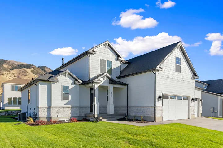 Modern farmhouse residence featuring a clean white exterior with dark roof accents, multiple gabled rooflines, and substantial front-facing garage with dual doors