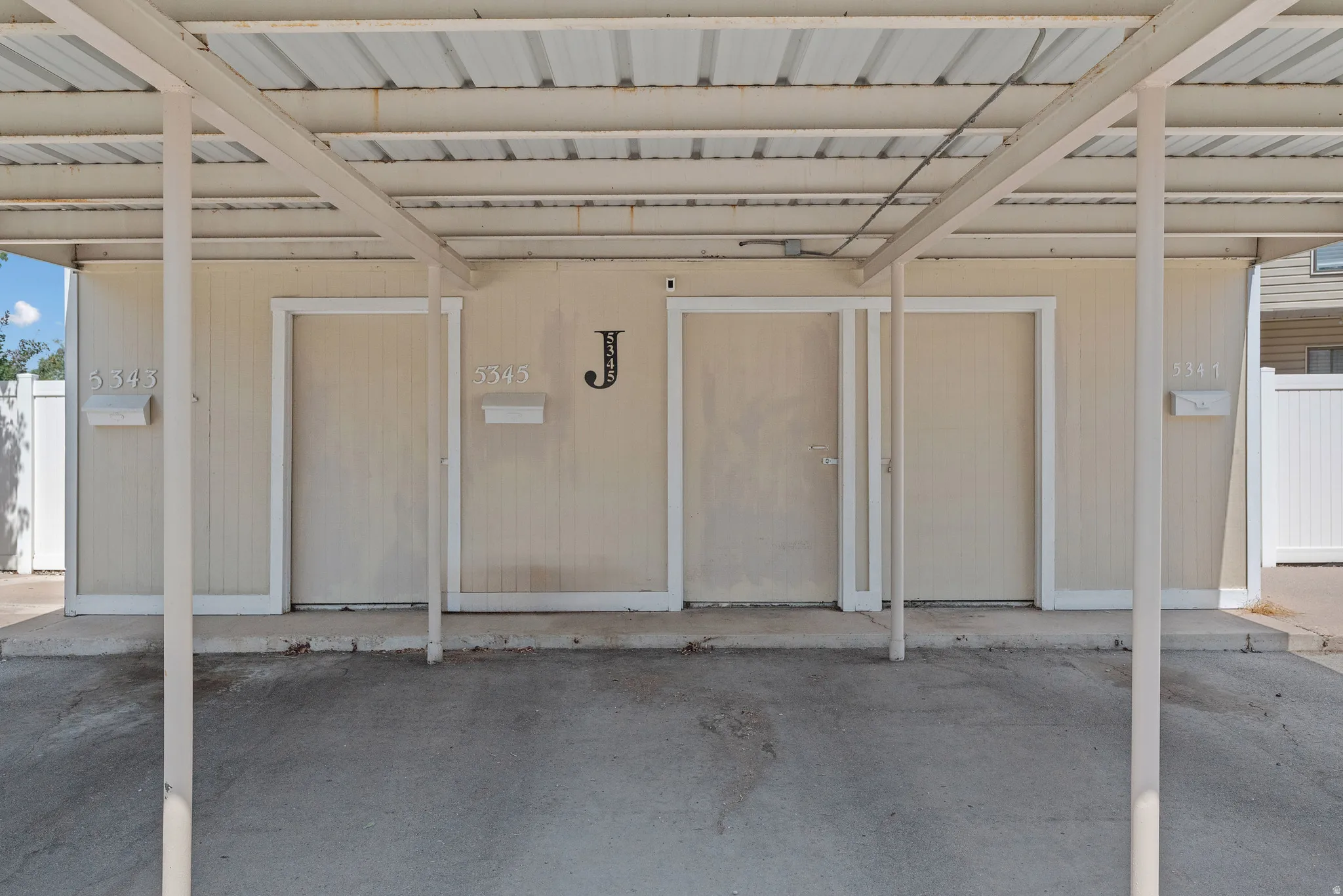 Covered carport parking space featuring a corrugated metal roof and four support columns