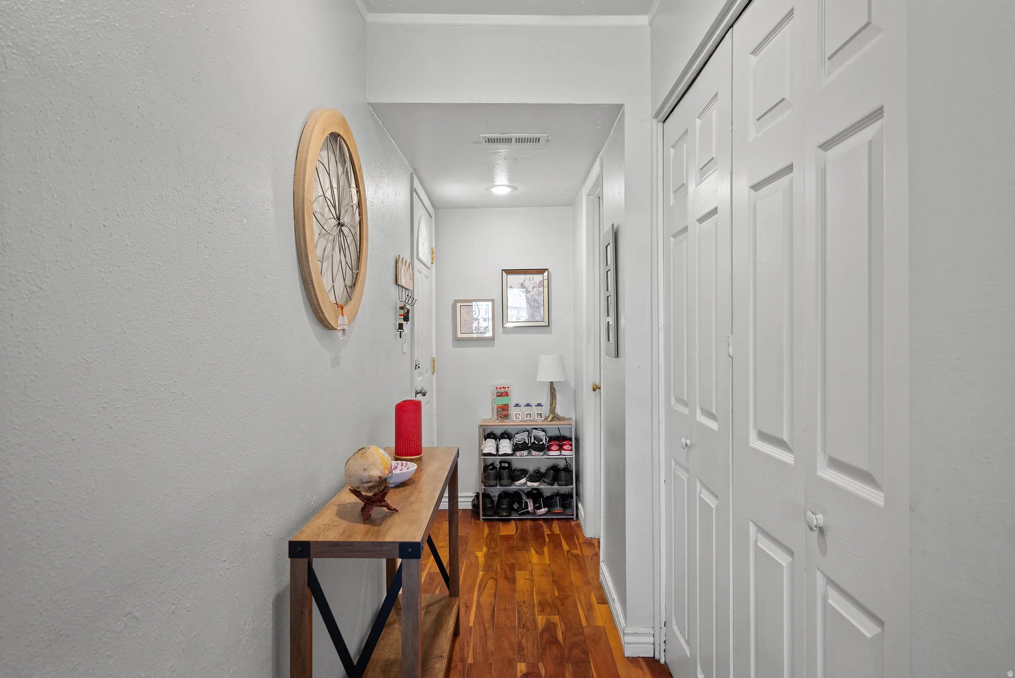 Hallway featuring wood-finish flooring, light-colored walls, and white bi-fold closet doors