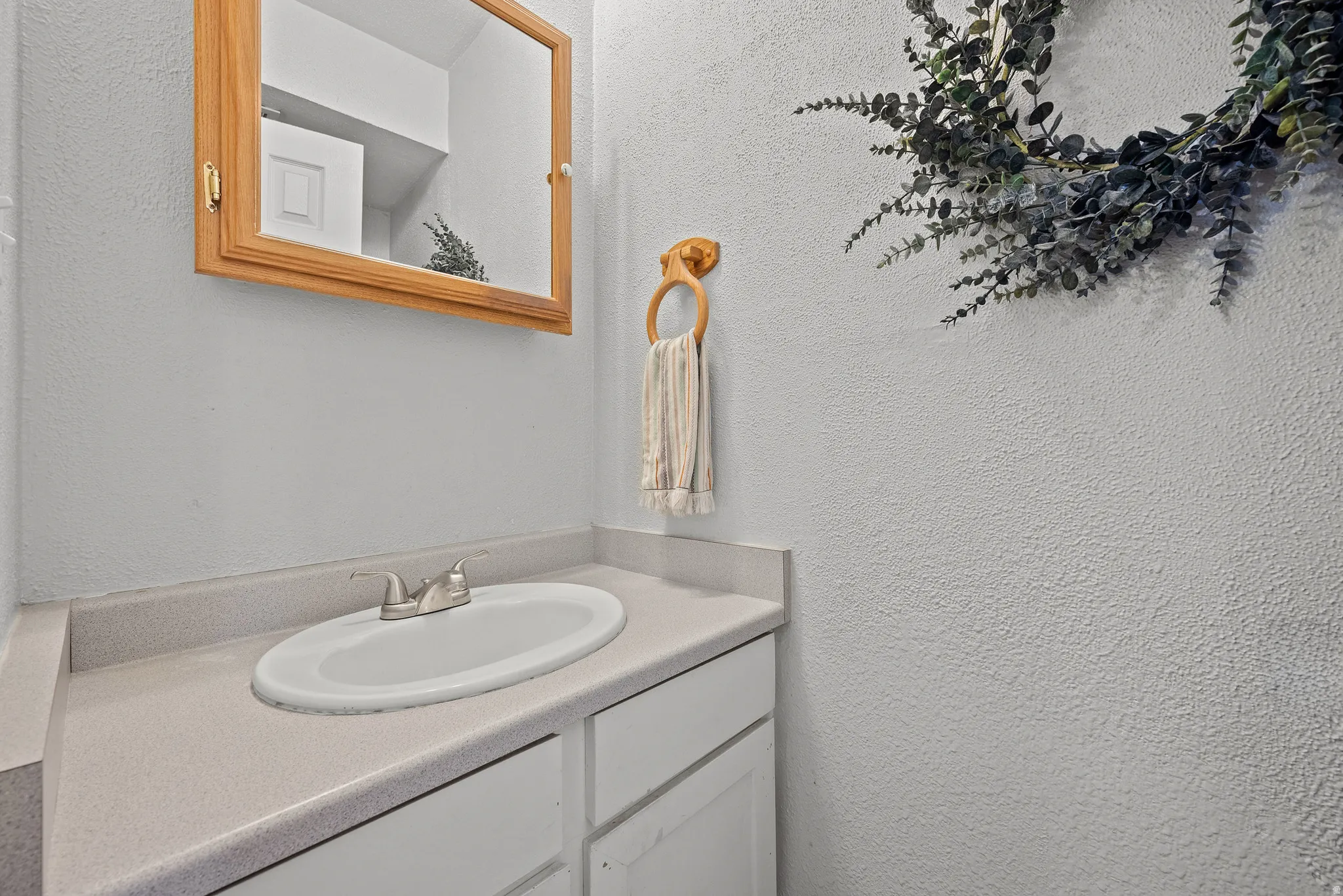 Vanity with integrated sink, brushed nickel faucet, and light-toned countertop