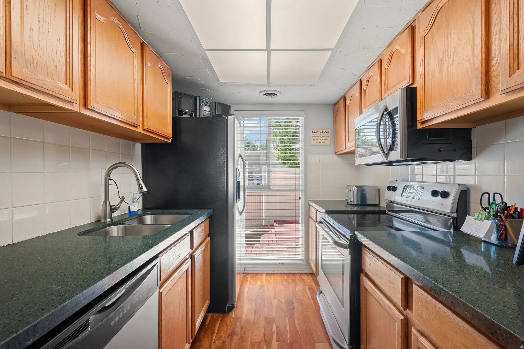 Galley kitchen featuring wood-finish flooring and light wood cabinetry