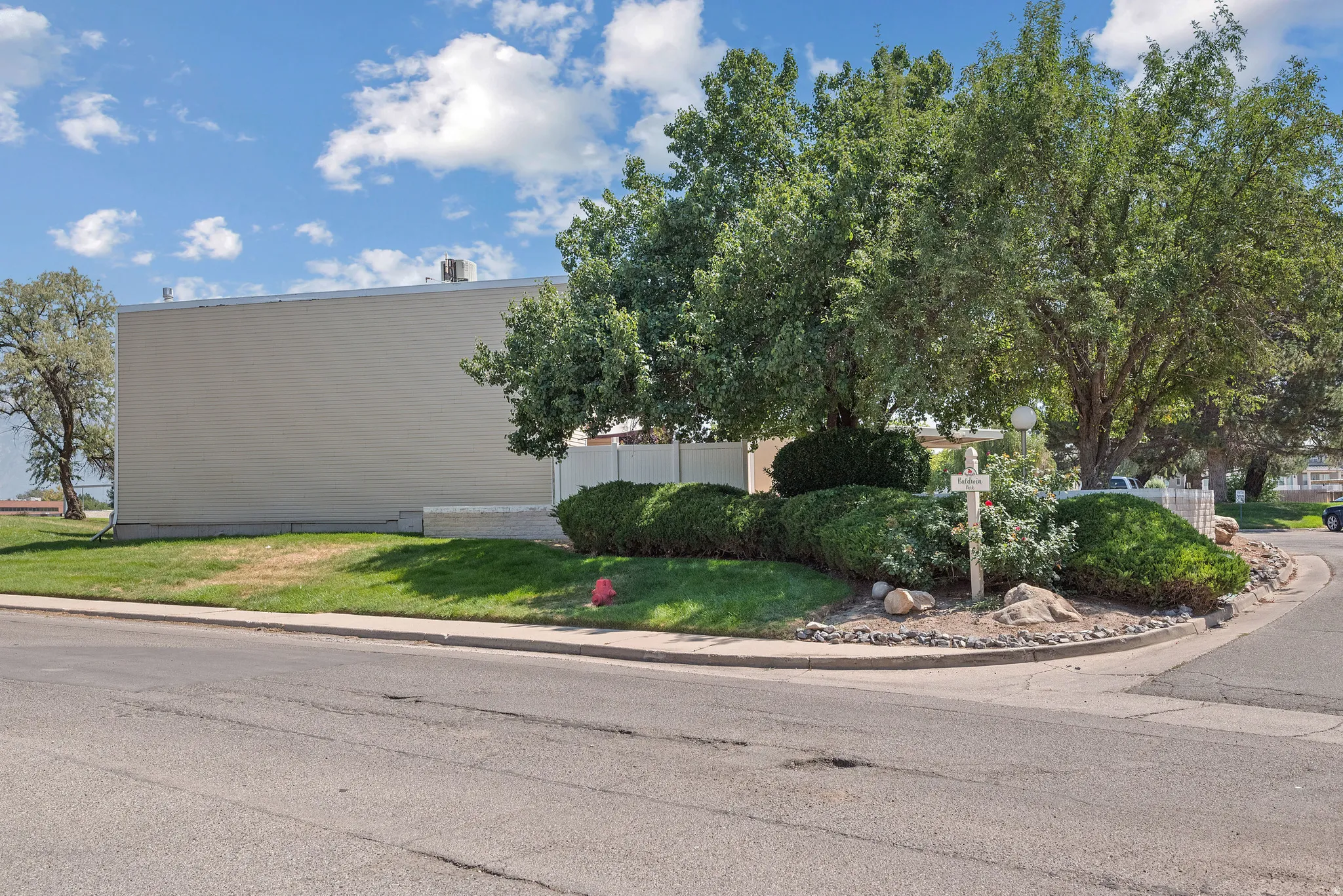 Corner lot featuring mature trees, established shrubbery, and a well-maintained lawn