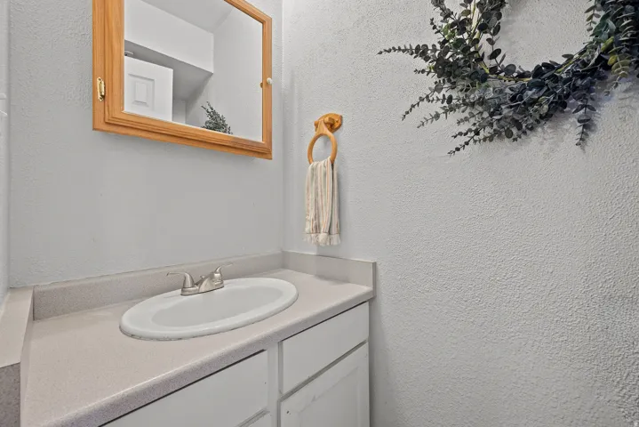Vanity with integrated sink, brushed nickel faucet, and light-toned countertop