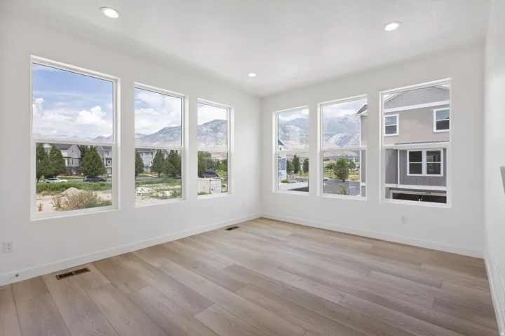 Bright room featuring wood-finish flooring, white walls, and six large windows