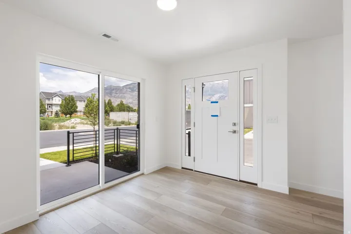 Entryway featuring light wood-finish flooring, white baseboards, and a contemporary front door with sidelights