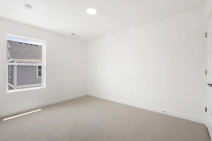 Room featuring a window with a white frame, light-colored carpeting, white baseboards, and a white ceiling with recessed lighting