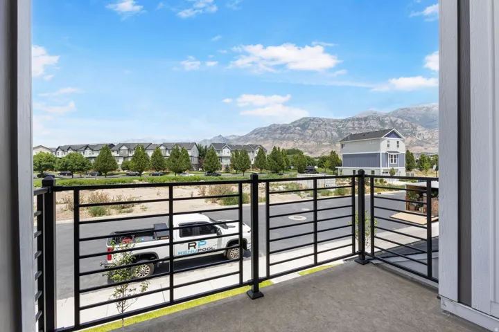 Balcony with dark metal railing, concrete flooring, and light-colored vertical siding