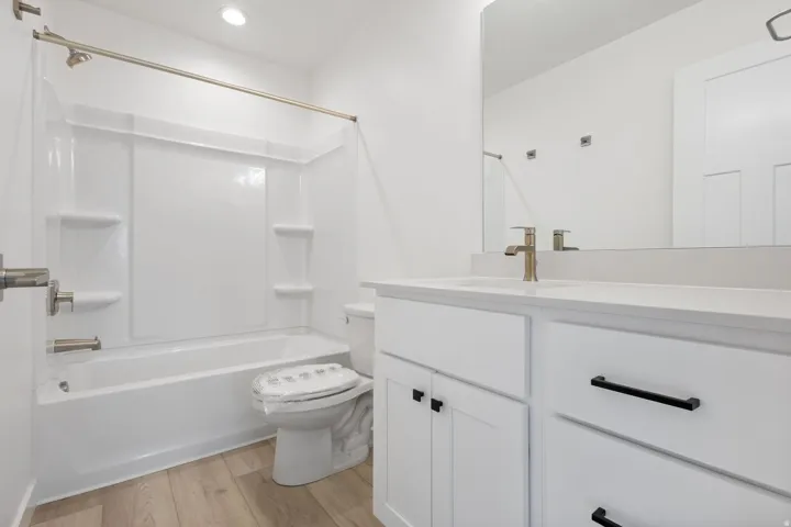 Bathroom featuring a white vanity with a light-toned countertop, brushed gold faucet, and a large mirror