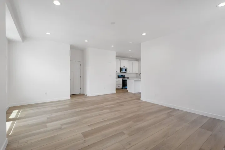 Spacious room featuring wood-finish flooring, recessed lighting, and a neutral color palette