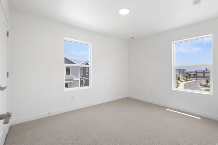 Bright interior space featuring two windows, neutral wall paint, and light-colored carpeting