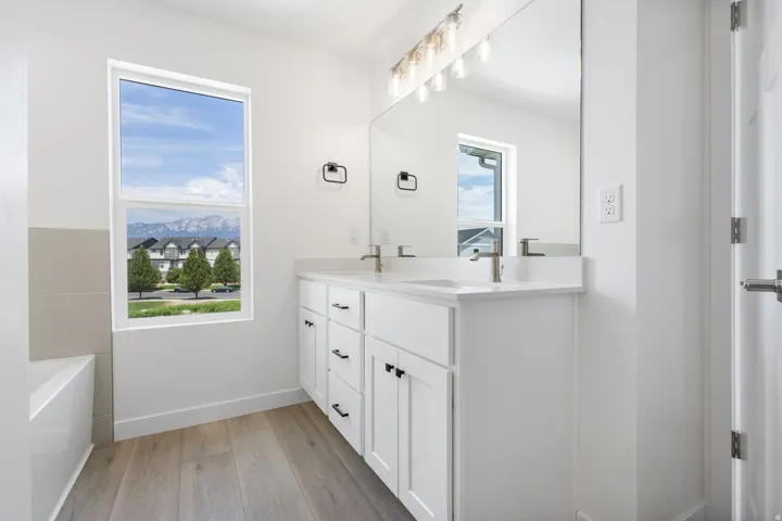 Double vanity with white cabinetry, brushed nickel faucets, and stone countertops