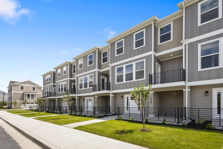Modern multi-story townhome featuring gray vertical siding with white trim