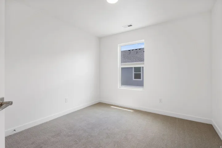 Bright room featuring a single window, overhead lighting, and neutral tone carpet