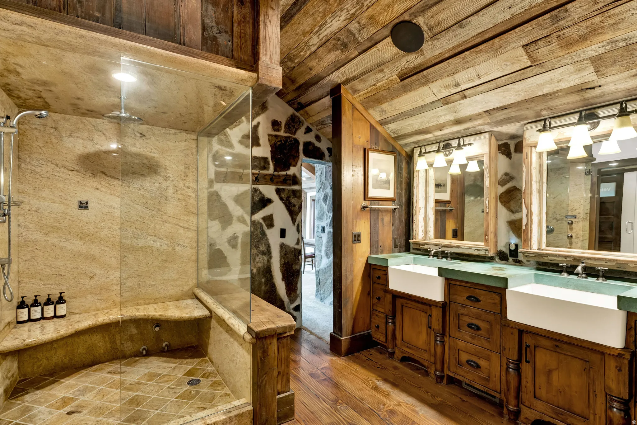 Spa-inspired master bath showcasing a walk-in shower with travertine tile surround, rainfall showerhead, and built-in niche storage