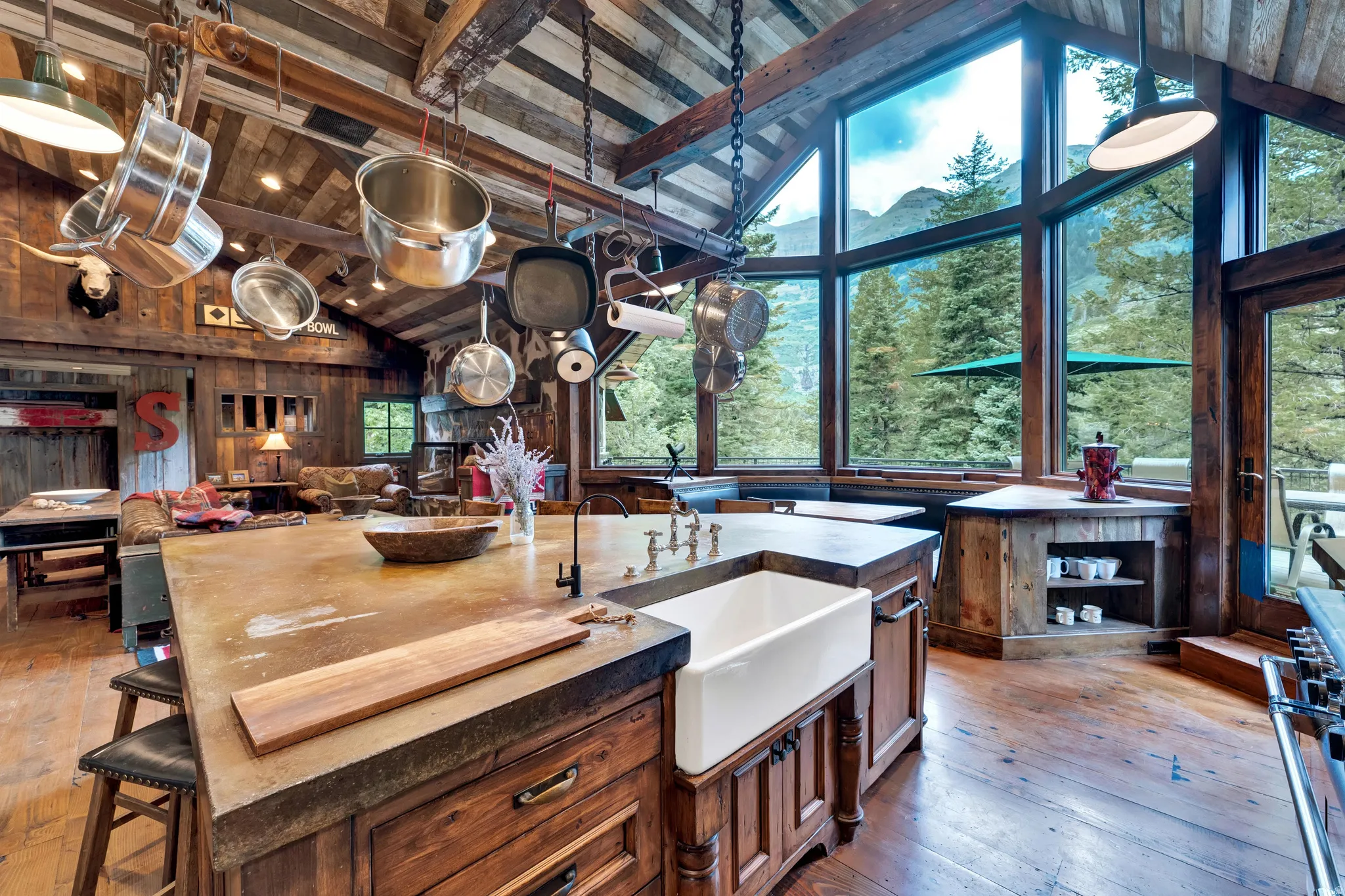 Chef's kitchen showcasing dual wood-finish islands with apron-front sink, professional-grade cookware storage, and stainless steel pendant lighting