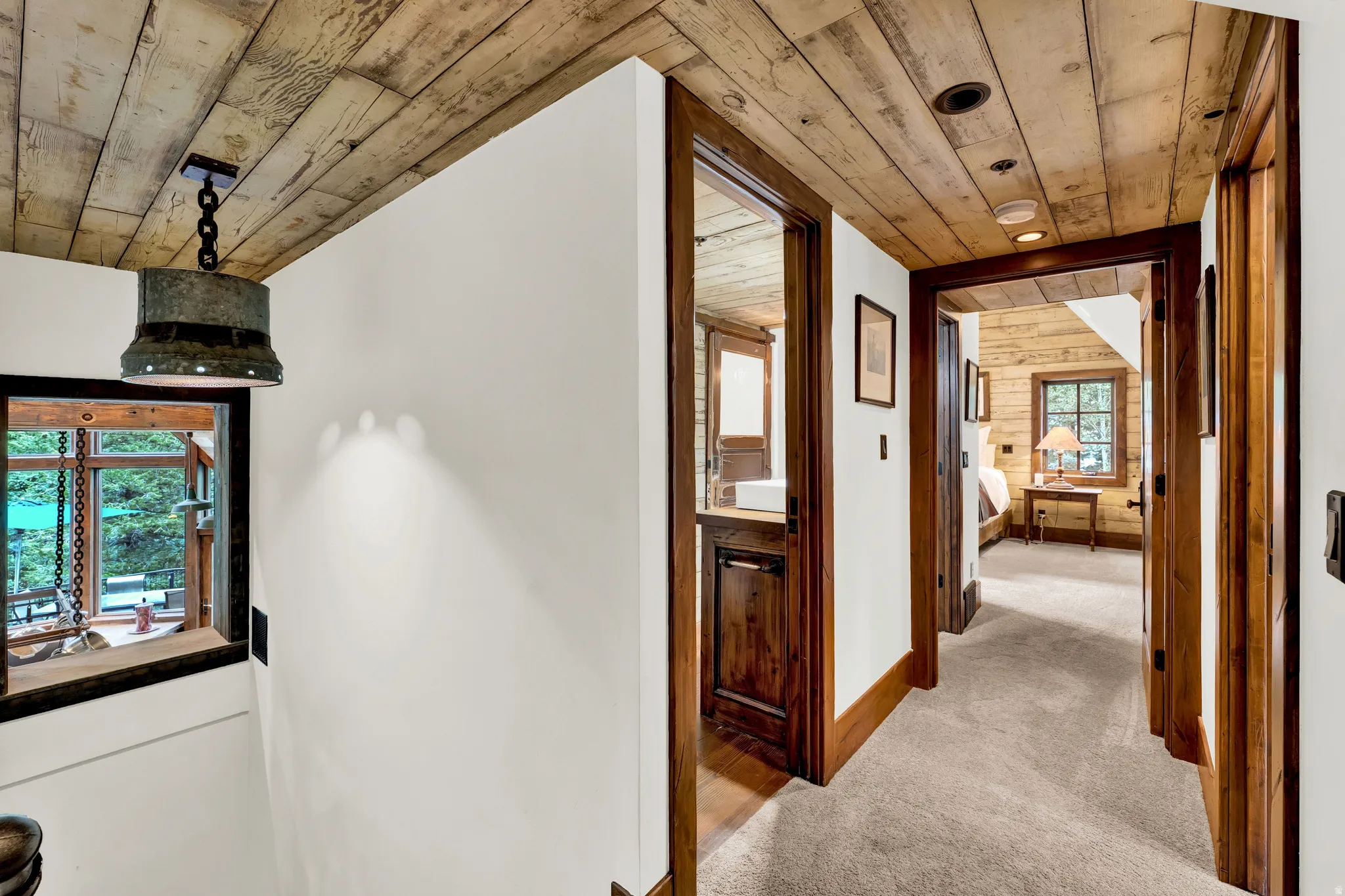 Rustic wood beam ceiling and hallway featuring rich wood-finish doors and frames, neutral carpeting, and recessed lighting throughout