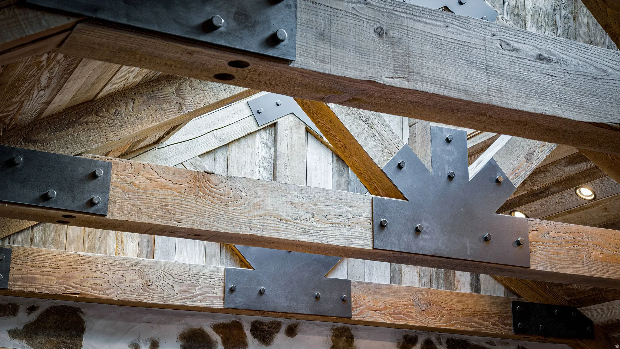 Striking exposed beam ceiling featuring substantial timber construction with steel plate connectors and brackets, creating dramatic architectural character and substantial vertical clearance in this distinctive interior space