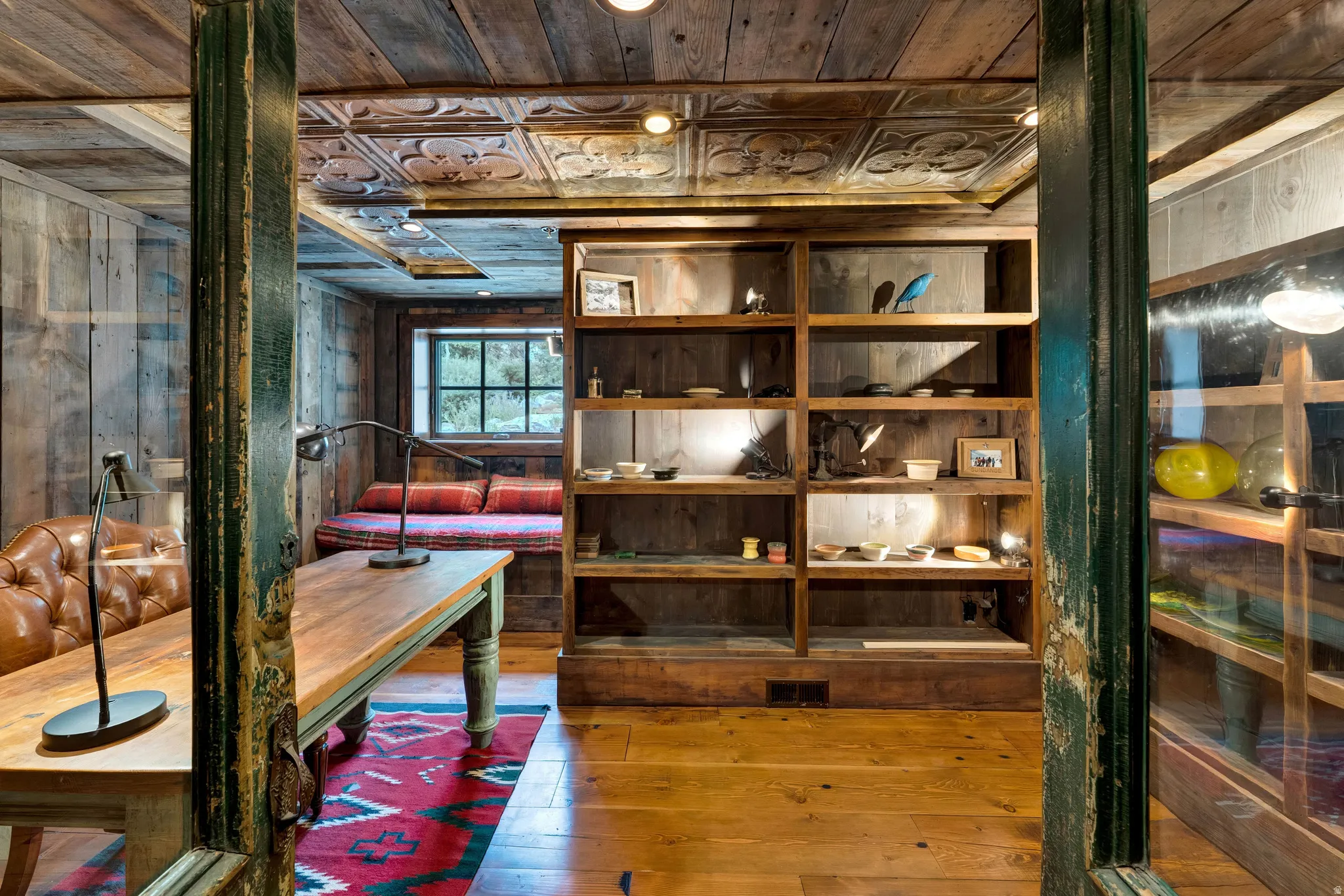 Sophisticated loft-style interior showcasing exposed timber ceiling beams, substantial green support columns, and wide-plank wood-finish flooring throughout