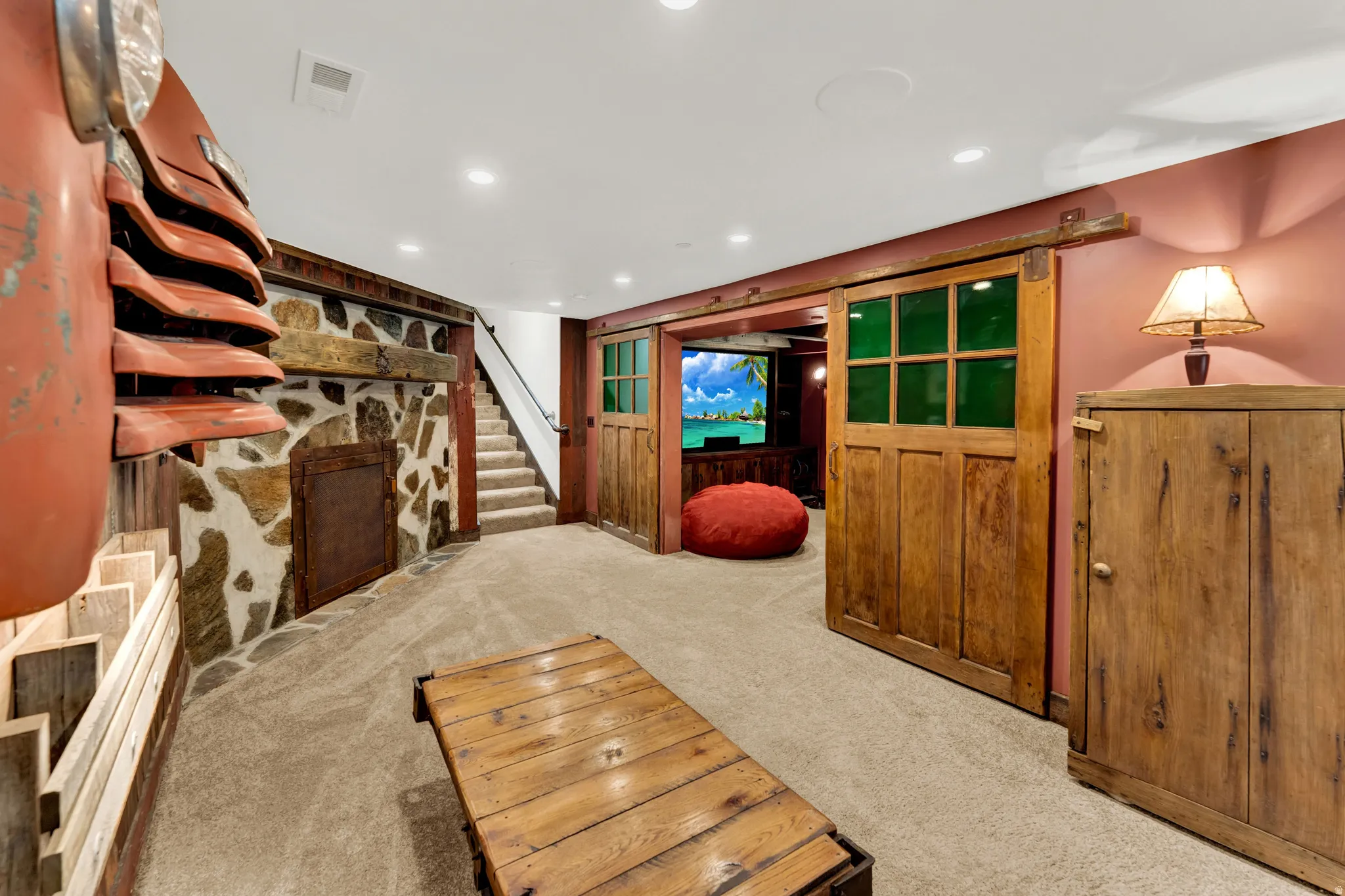 Recreation space featuring a stone accent wall with a wood beam mantel, carpeted flooring, and recessed lighting