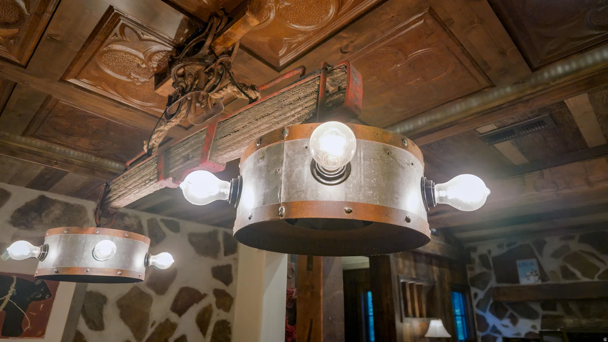 Elegant ceiling fixture featuring brushed metal drum shade with integrated globe lights and ornamental wooden beam detail