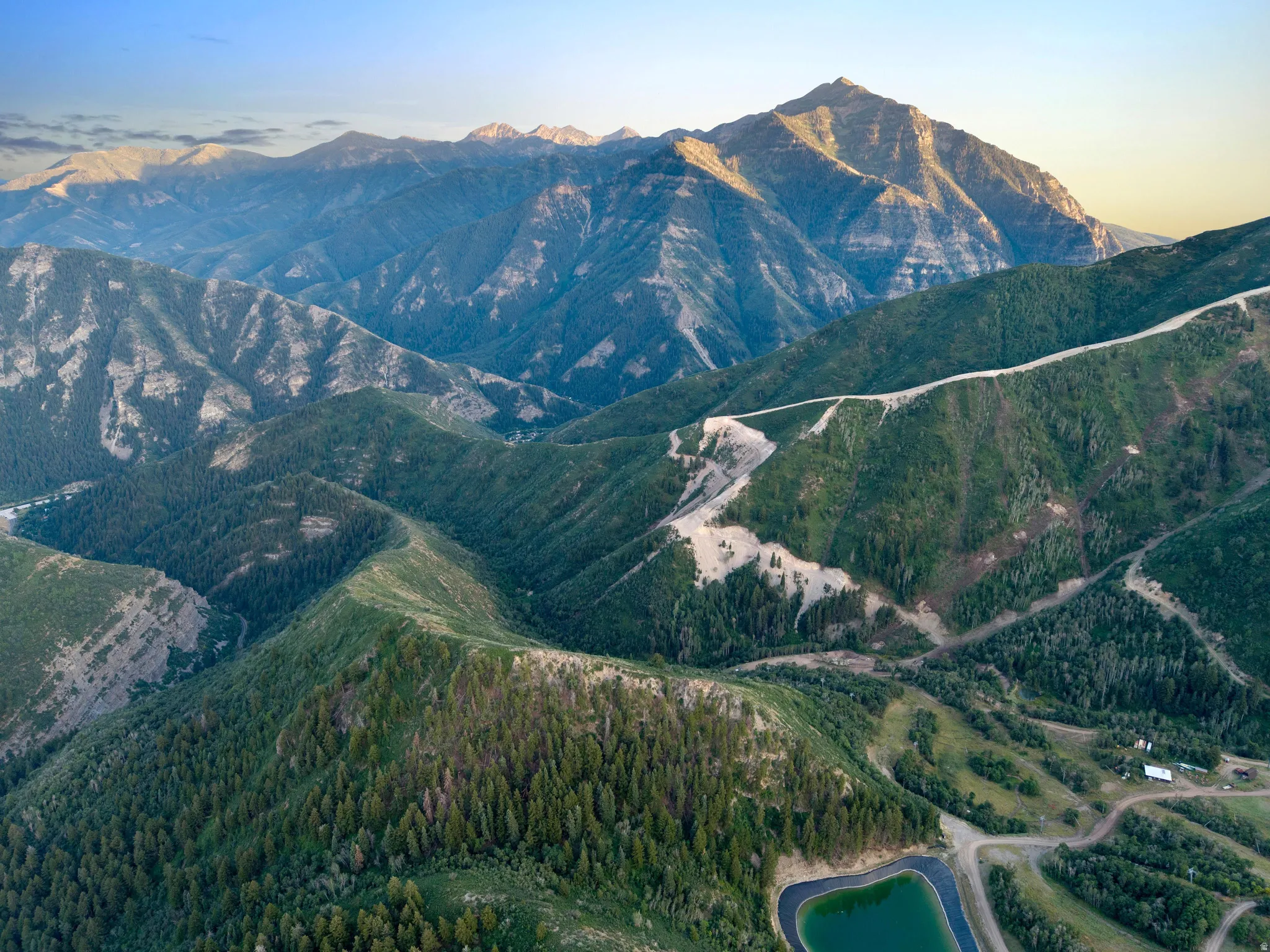 Expansive mountain landscape featuring rugged peaks and verdant tree-covered slopes