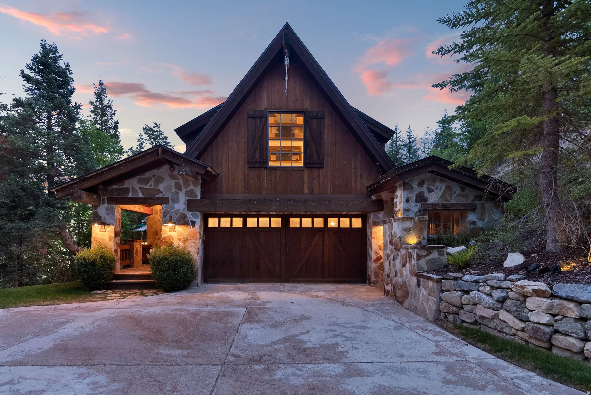 Modern A-frame residence featuring a striking dark wood and stone exterior with illuminated multi-pane gable window