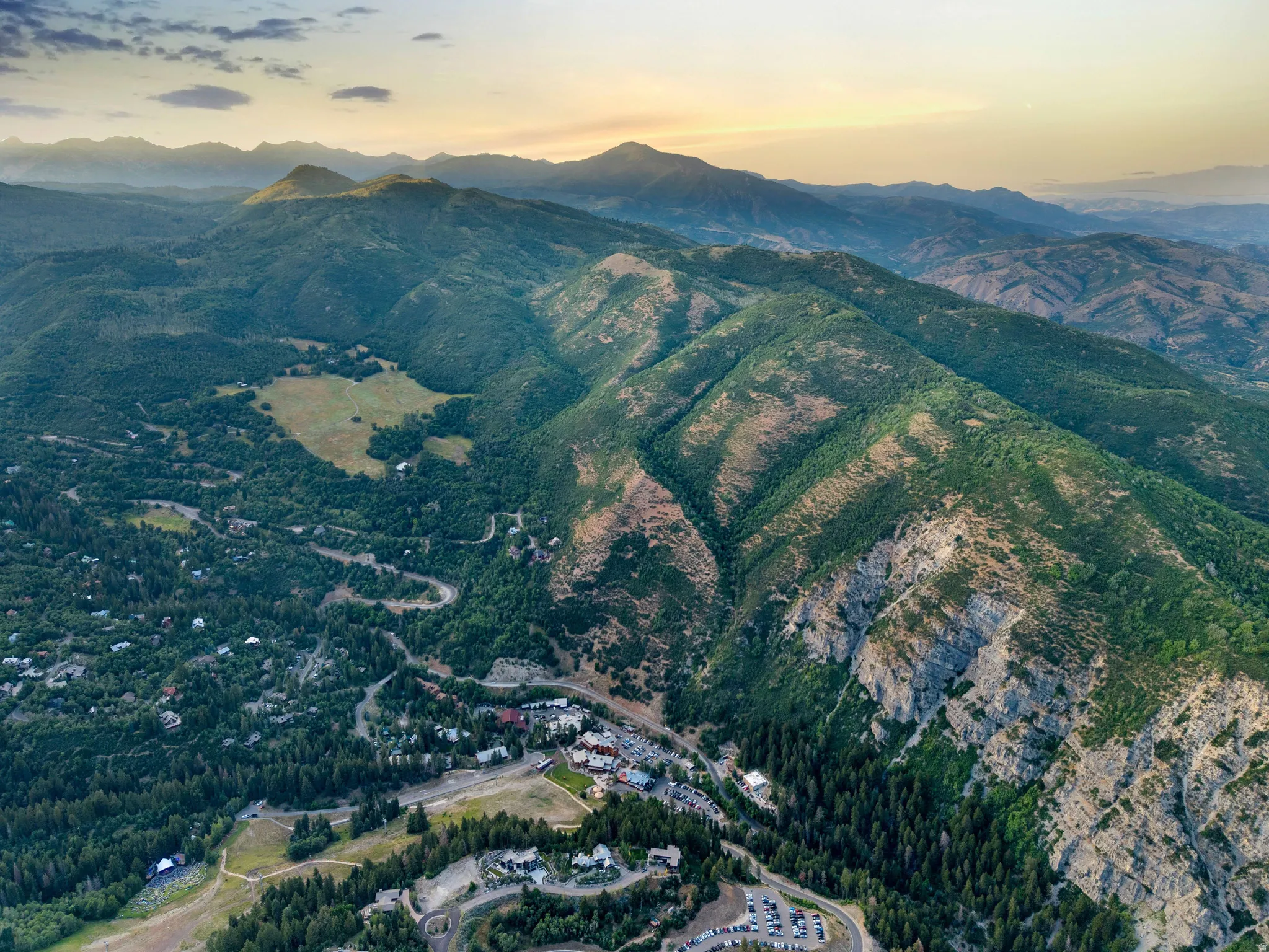 Spectacular aerial perspective showcasing expansive forested terrain with rolling mountain ridges, alpine lake, and established residential community nestled throughout the valley