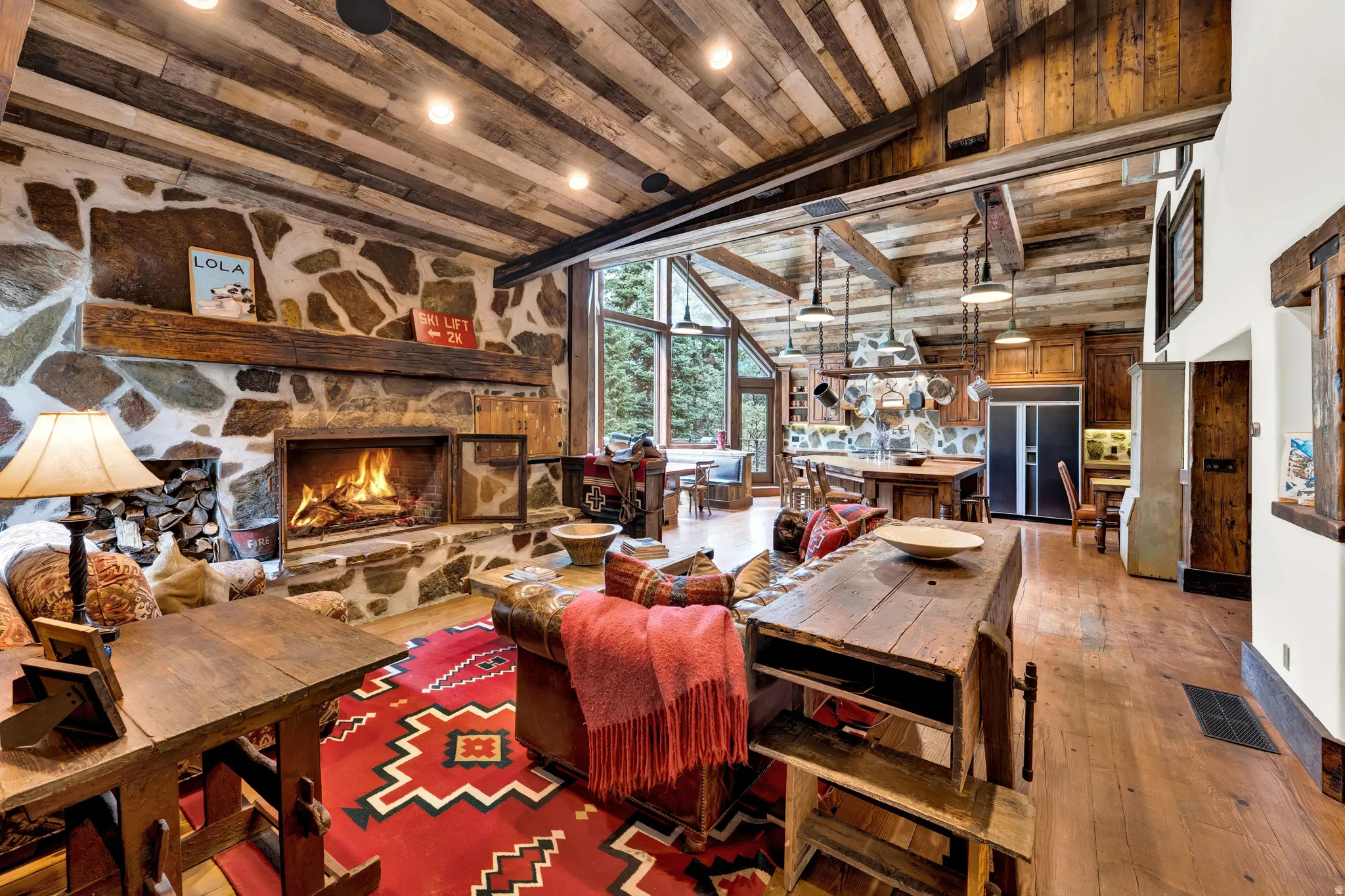 Expansive open-concept living space anchored by a wood-burning fireplace with stone surround and substantial wood mantel